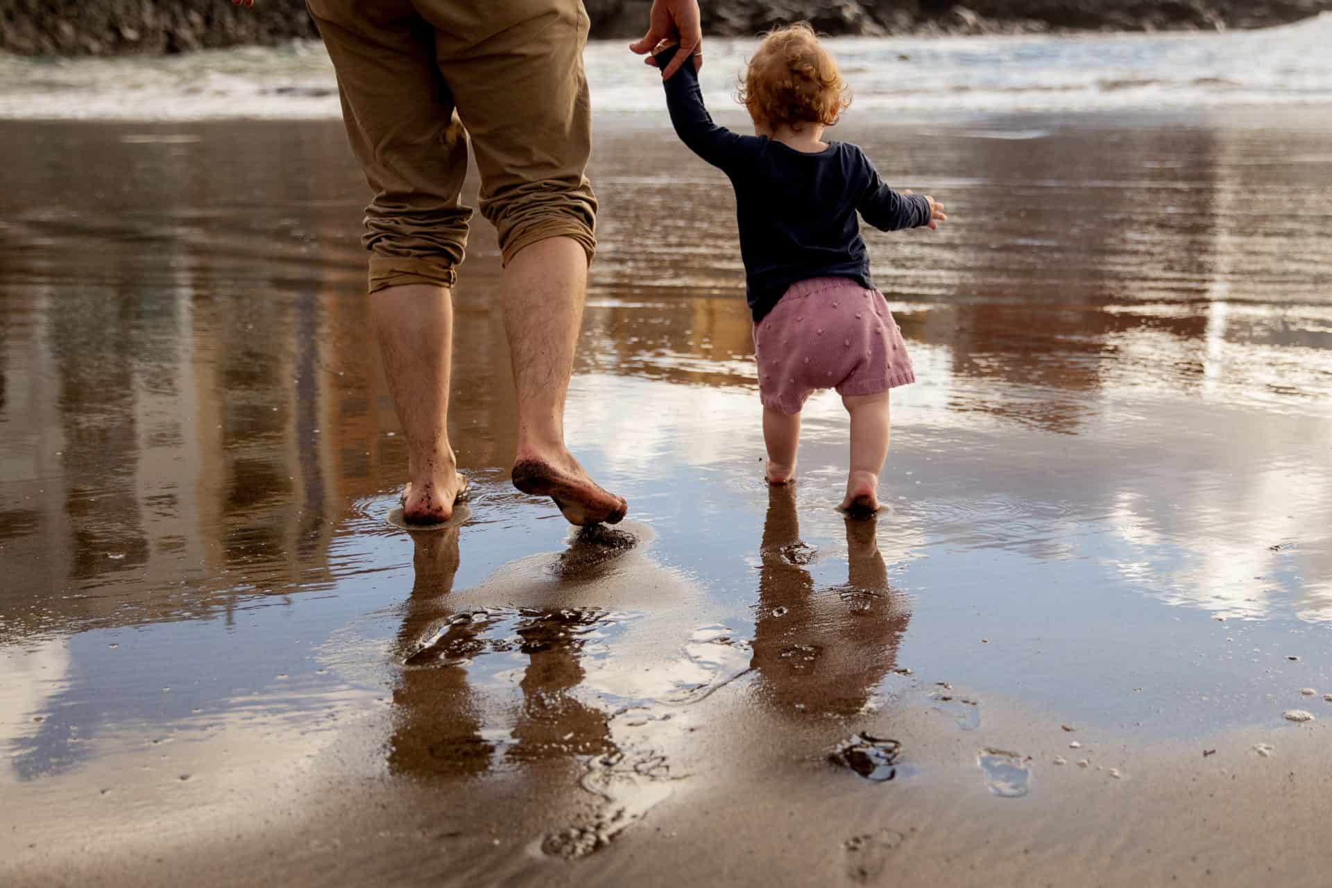 Na plaży - ojciec trzymający dziecko za rękę